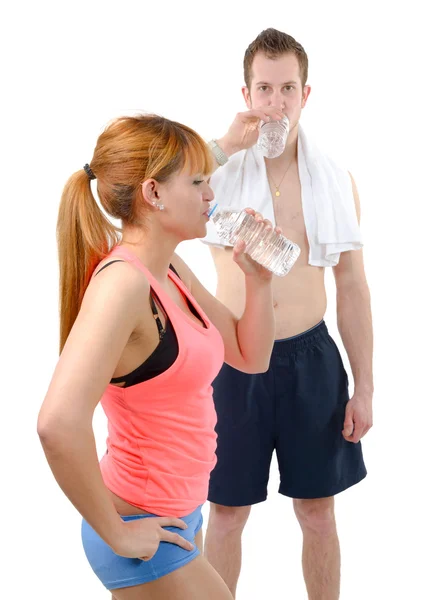 水のボトルを保持しているフィットネスの服装で体育館で男女 — ストック写真