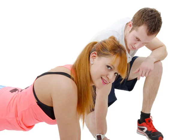 Male trainer assisting young woman doing push-up Stock Image