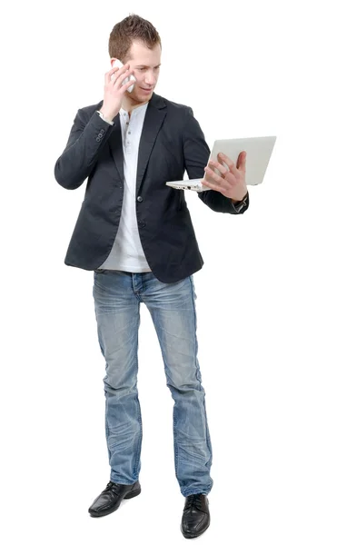 Jeune homme debout avec ordinateur portable et téléphone — Photo