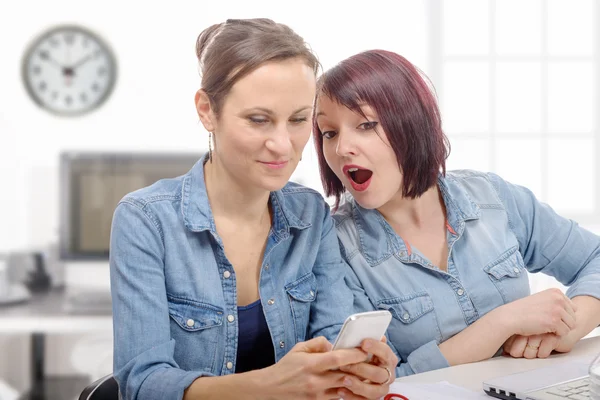 Smiling businesswomen using cell phone in office — Stock Photo, Image