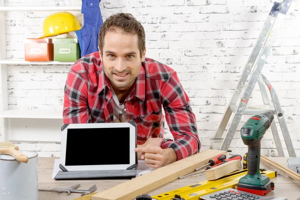 smiling young carpenter showing  screen on digital tablet