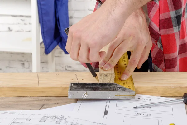 Carpenter draws a plank with a pencil — Stock Photo, Image