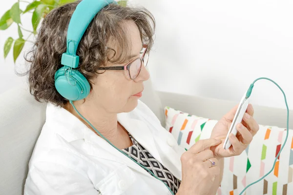 Зрелая женщина слушает музыку в наушниках — стоковое фото