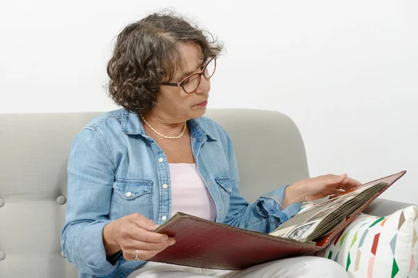 Middle-aged woman looking at photo album — Stock Photo, Image