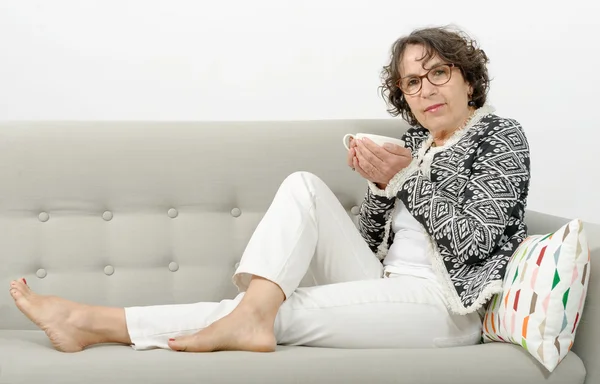 Mujer madura bebiendo té en el sofá — Foto de Stock