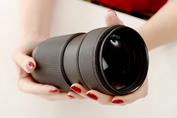 Mains d'une femme avec un objectif de caméra — Photo