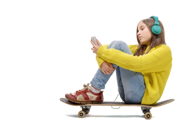 Симпатичная молодая девушка позирует сидя на коньках, слушает музыку — стоковое фото