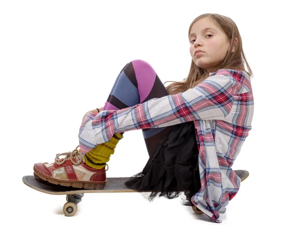 Ganska ung flicka sitter på skate, på vitt — Stockfoto