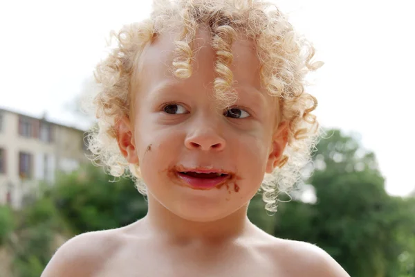 Menino loiro com chocolate na boca — Fotografia de Stock