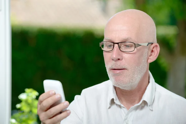 Starszy człowiek, czytanie wiadomości na smartfonie — Zdjęcie stockowe