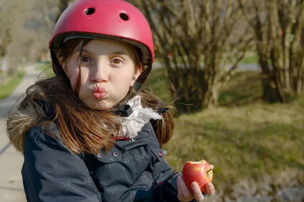 Preteen met roller skate helm, eet een appel — Stockfoto