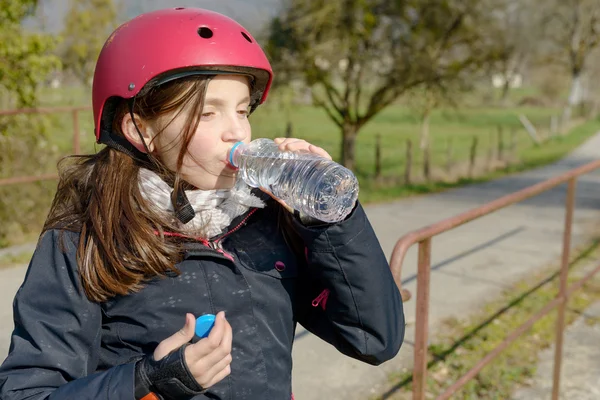 Tenåring med rulleskøytehjelm, drikke vann – stockfoto
