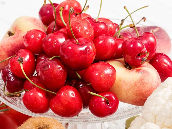 Wiśnie i brzoskwinie na biały drewniany stół — Zdjęcie stockowe