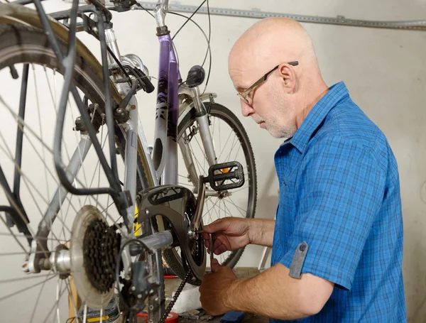 Hombre reparando bicicleta en su taller . — Foto de Stock