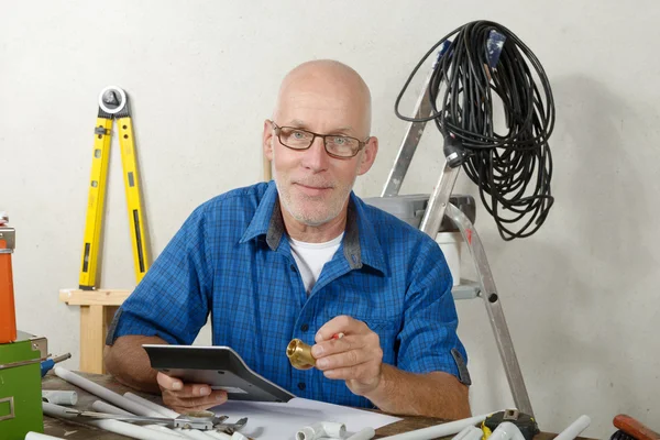 Loodgieter met een digitaal tablet in zijn atelier — Stockfoto