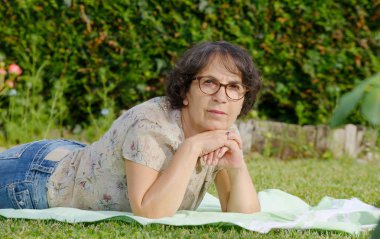 Orta yaşlı bir kadın bahçede dinleniyor