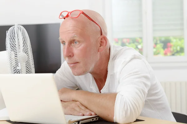 Mature man with a laptop in the house — Stock Photo, Image