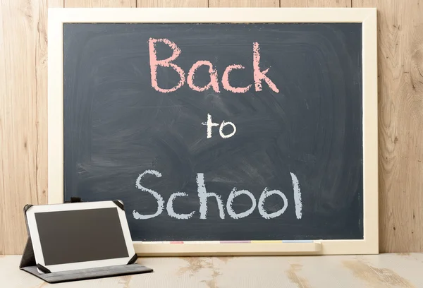 Back to school written on blackboard with tablet — Stock Photo, Image