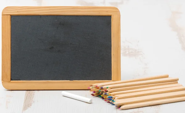 Chalkboard and colouring pencils — Stock Photo, Image