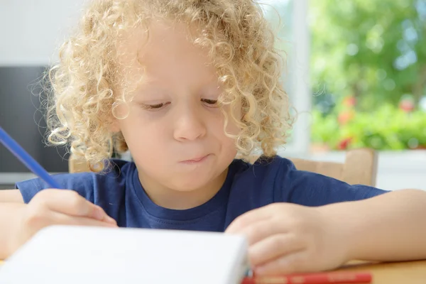 Jongen puttend uit een notebook — Stockfoto