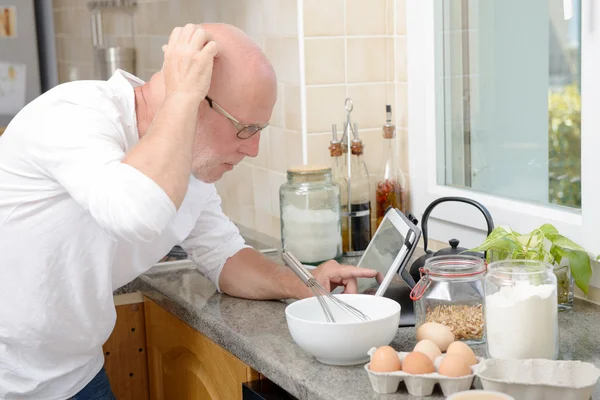 senior man in kitchen using  tablet