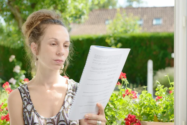 Młoda kobieta czyta w pobliżu okna — Zdjęcie stockowe