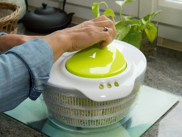 Mão de uma mulher fiação salada na cozinha — Fotografia de Stock