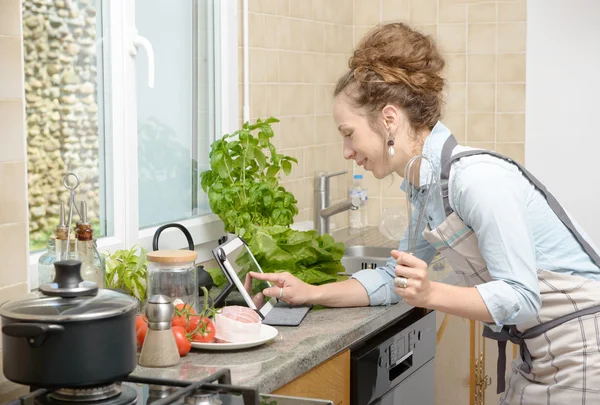Uśmiechnięta młoda kobieta przy użyciu tabletu do gotowania — Zdjęcie stockowe