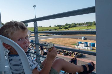 Dondurma yiyen ve karting yarışına giden küçük bir çocuk.