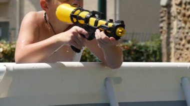 Genç çocuk su tabancasıyla oynuyor.