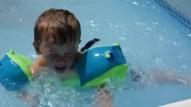 Küçük çocuk yüzme havuzunda oynuyor.