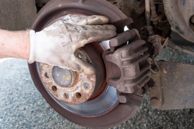 Araba tamircisi arabanın frenlerini tamir ediyor.
