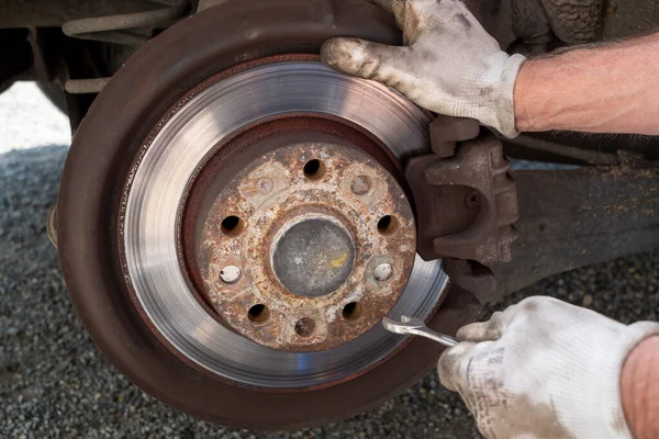 a Car mechanic repairing brakes on car