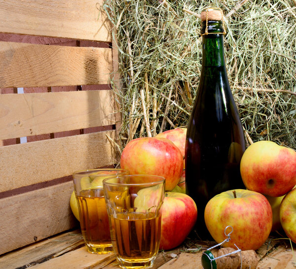 bottle of cider with some apples and straw