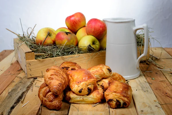 Croissants and pains au chocolat with a box of apples — Stock Photo, Image