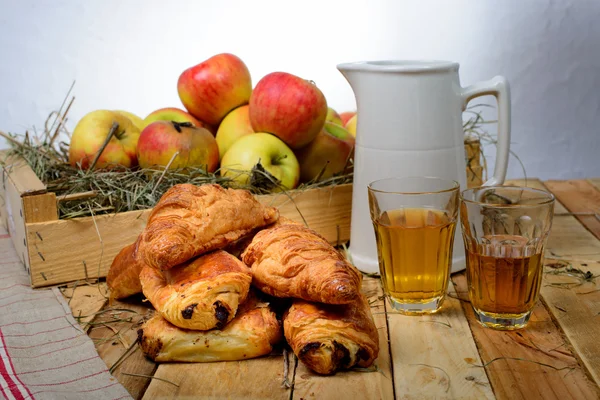 Croissants e dores au chocolat com uma caixa de maçãs — Fotografia de Stock