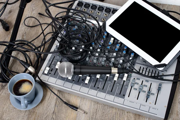 Tablet digital colocado em um mixer de áudio com um café — Fotografia de Stock