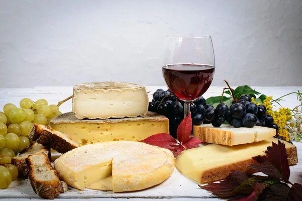 Diferentes queijos Savoie com um copo de vinho tinto — Fotografia de Stock