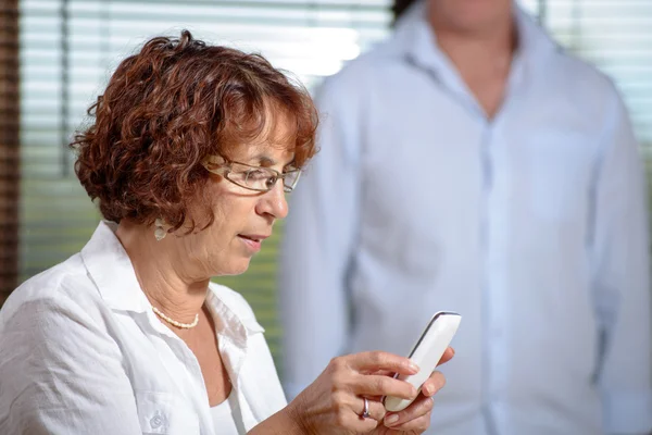 Egy magas rangú nő egy kanapé, a telefon — Stock Fotó