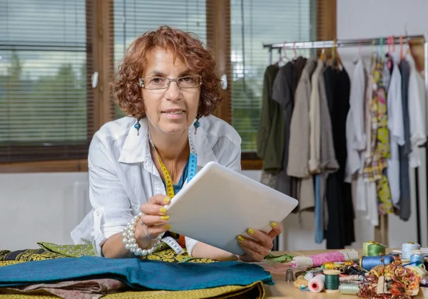 Schneidermeister schaut in seiner Werkstatt auf ein digitales Tablet — Stockfoto