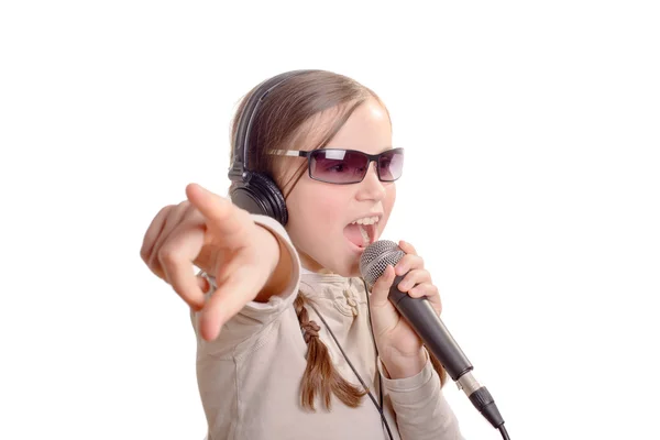 A young girl with headphones singing with a microphone — Stock Photo, Image