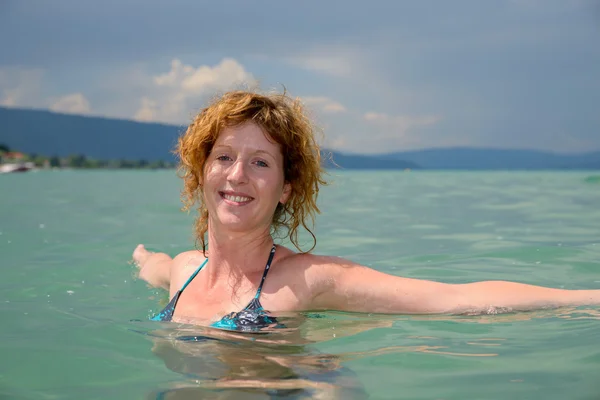 Piękna młoda kobieta pływa w jeziorze — Zdjęcie stockowe