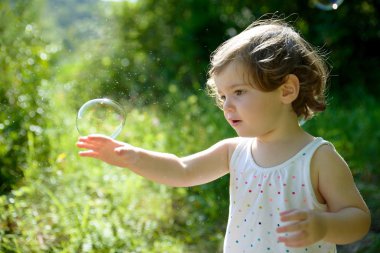 a little girl playing with soap bubbles clipart