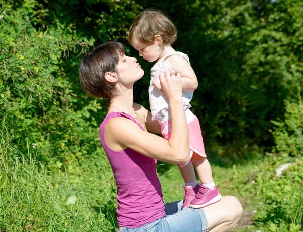 En vacker mamma är en kram till sin dotter i naturen — Stockfoto