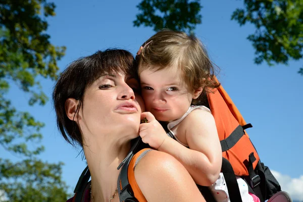 A little girl in a baby carrier walks with his mom — Stock Photo, Image