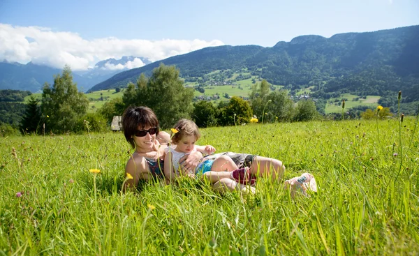 Eine schöne Mutter und Tochter im Gras liegend — Stockfoto