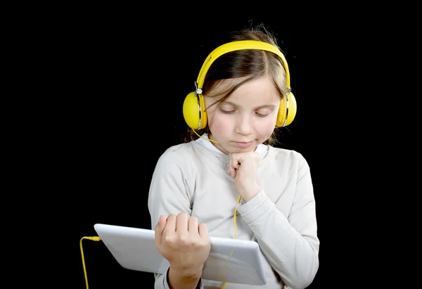 Una joven con auriculares amarillos y una tableta digital —  Fotos de Stock