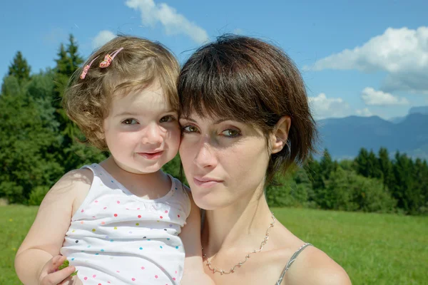 Uma bela mãe é um abraço para sua filha na natureza — Fotografia de Stock