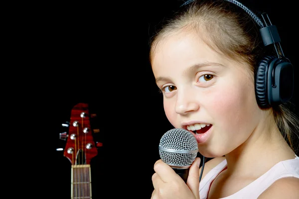 Młoda dziewczyna z słuchawki śpiewa z mikrofonem — Zdjęcie stockowe