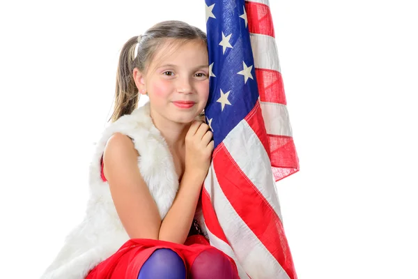 Ein hübsches kleines Mädchen sitzt auf einer Schachtel mit einer amerikanischen Flagge — Stockfoto